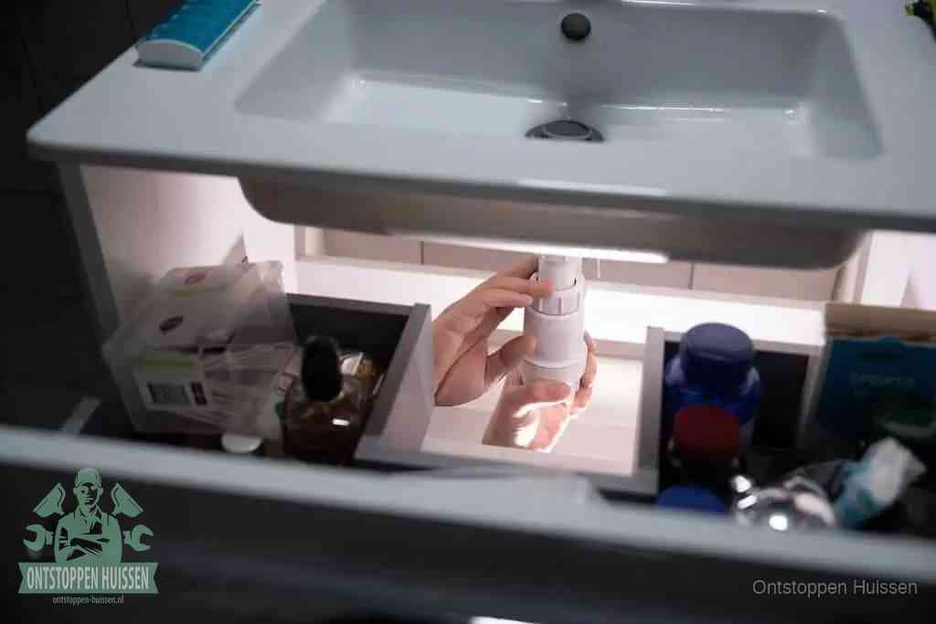 Een pompfles met zeep boven een wastafel, de heet water en afwasmiddel-methode om een vetprop in de afvoer los te maken in Huissen