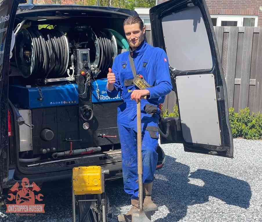 Een monteur bij de werkbus met grote hogedruk-slanghaspels, apparatuur voor hardnekkige afvoerverstoppingen in Huissen