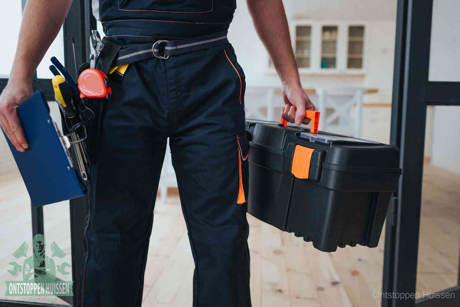 Een monteur met gereedschapsriem en klembord, klaar om een transparante prijs voor het afvoer ontstoppen in Huissen te geven