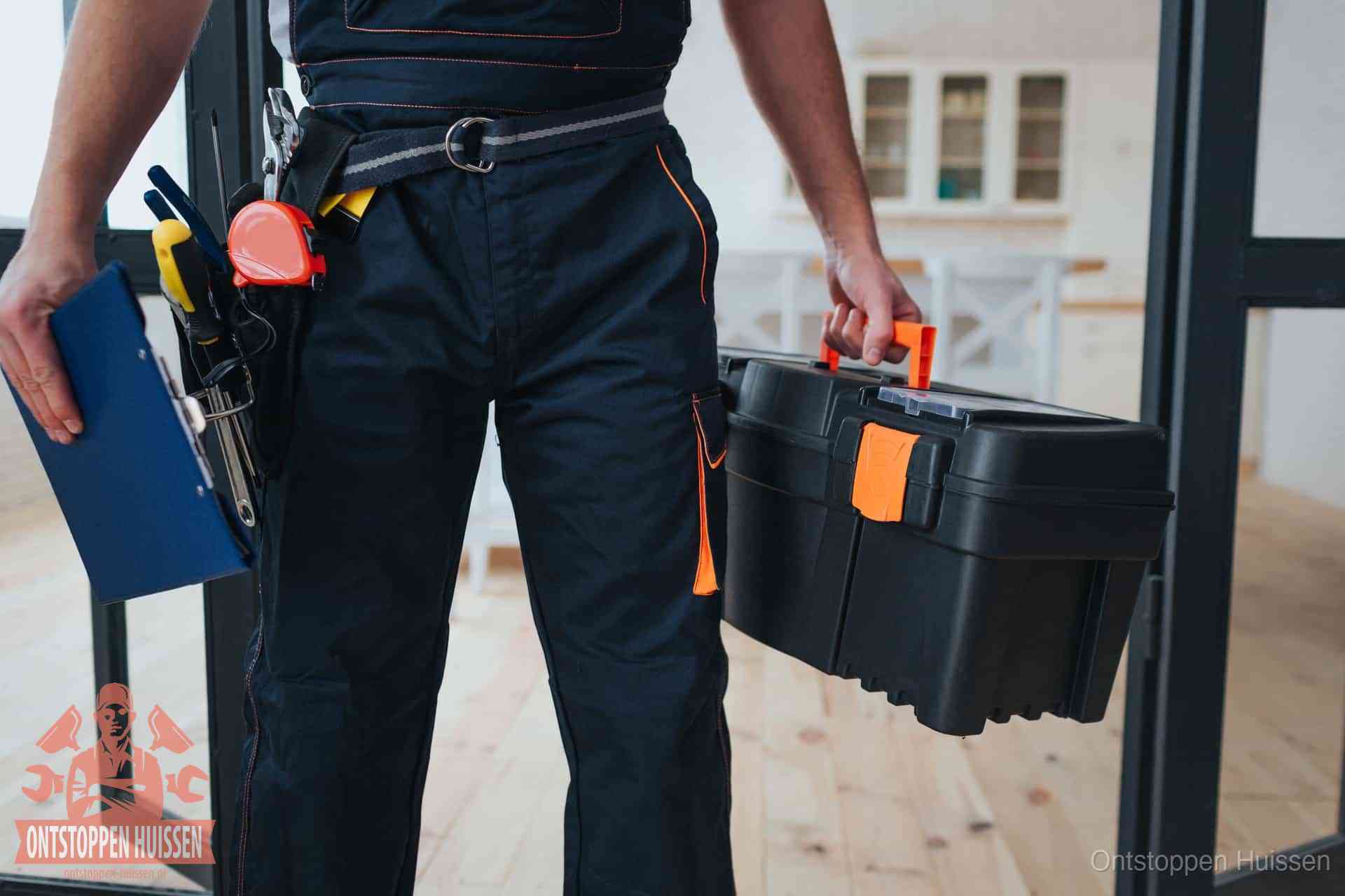 Een monteur met gereedschapsriem en klembord in een keuken, klaar om een transparante prijs voor het gootsteen ontstoppen in Huissen te geven