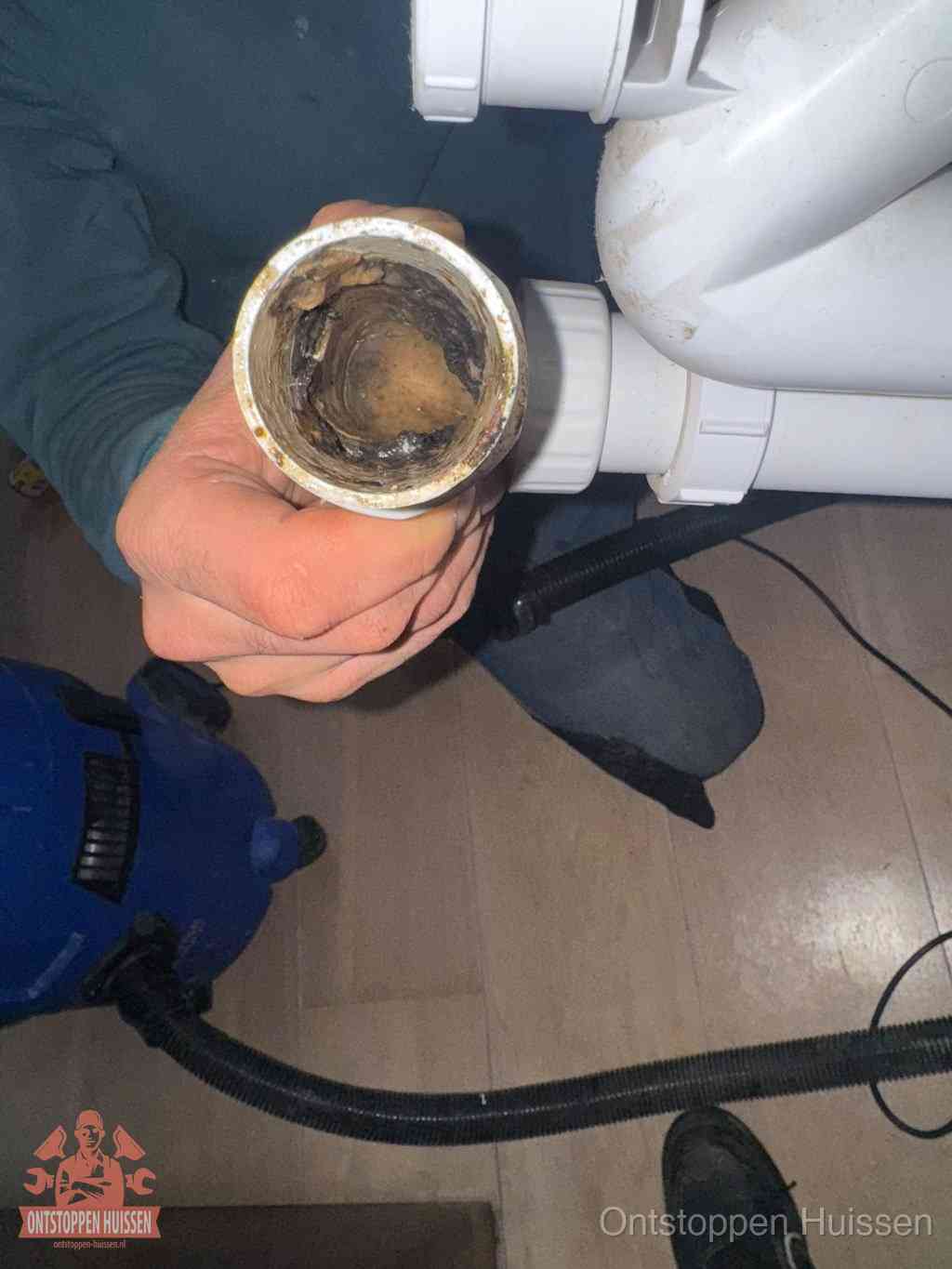Een losgekoppelde afvoerbuis die van binnen volledig is dichtgeslibd met vet en aanslag, de meest voorkomende oorzaak van een verstopte gootsteen in Huissen