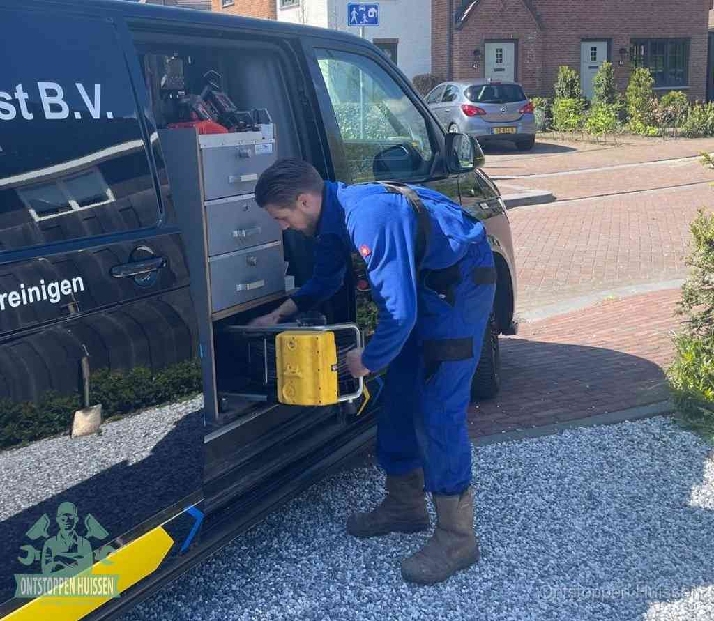 Een monteur pakt buiten op de oprit gereedschap uit de bedrijfsbus, het moment om een professional in te schakelen voor een verstopte afvoer in Huissen