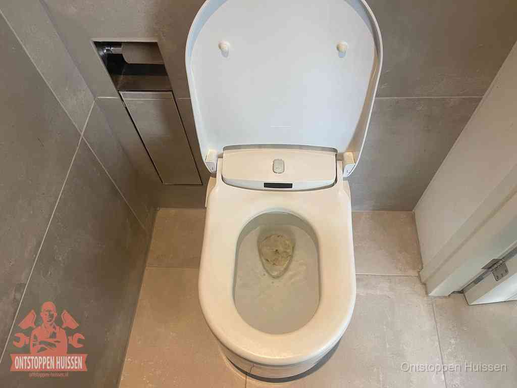 Een wit hangtoilet waarin een prop wc-papier op het water blijft drijven, een duidelijk signaal van een verstopte wc in Huissen