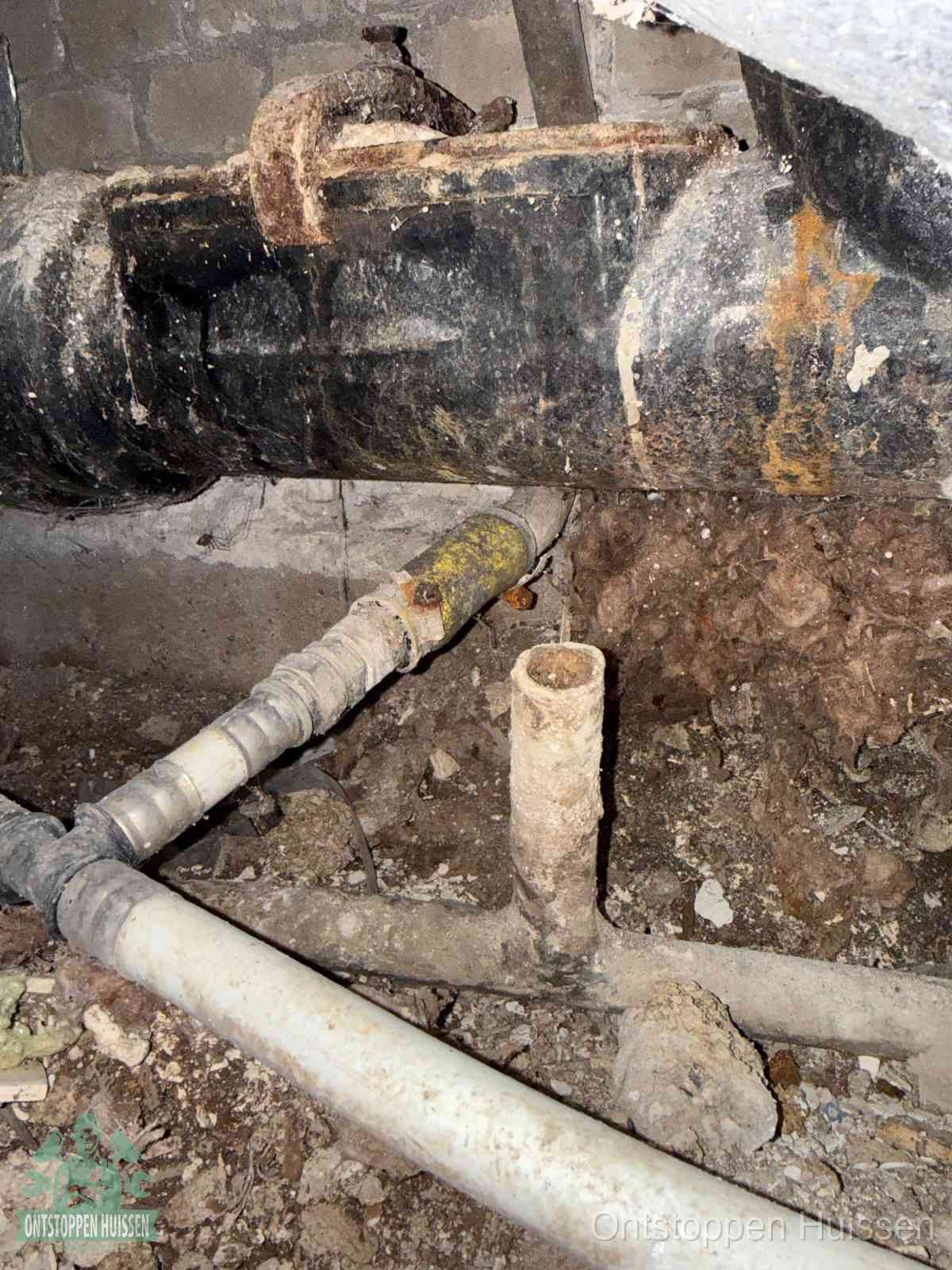 Een dikke zwarte hoofdrioolbuis met roest- en kalkaanslag in een kruipruimte, oorzaak van terugkerende structurele afvoerproblemen in Huissen