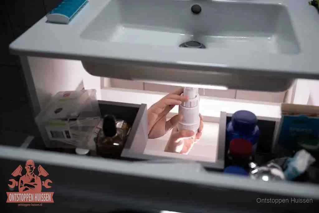 Een pompfles met zeep boven een wastafel in de toiletruimte, de warm water en afwasmiddel-methode om de wc te ontstoppen in Huissen