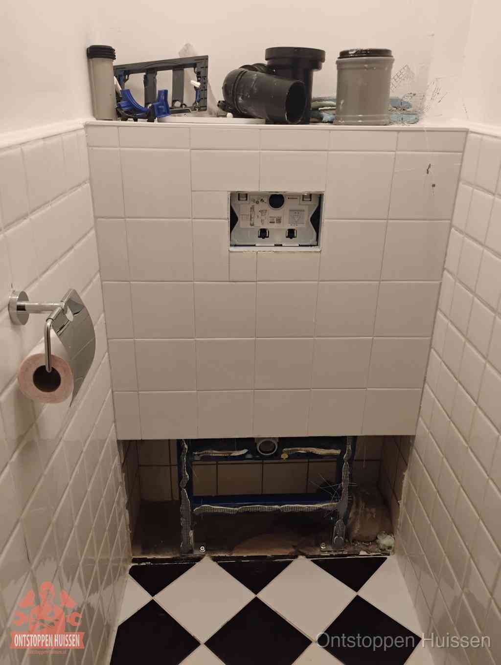 Een toiletruimte waar het hangtoilet en de inbouwreservoir-onderdelen zijn vrijgelegd voor onderhoud, periodiek nazicht voorkomt een wc-verstopping in Huissen