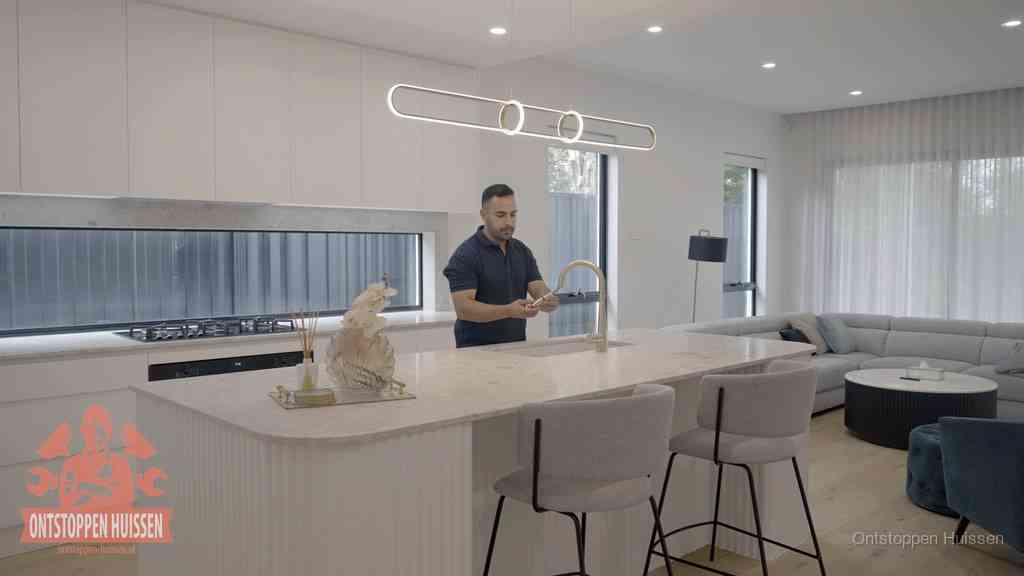 Een bewoner bij de keukenspoelbak die zelf aan de slag gaat met een verstopte gootsteen in Huissen